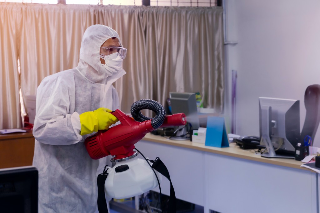 man in PPE Kit Spraying Disinfectant