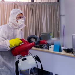 man in PPE Kit Spraying Disinfectant